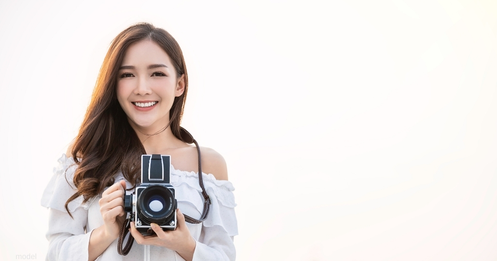 woman smiling while holding a camera